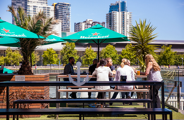 People dining at a pub by the docks of the Yarra River on a sunny day.